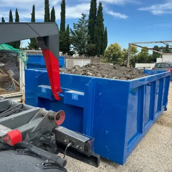 Benne bleue remplie de terre posée sur un chantier
